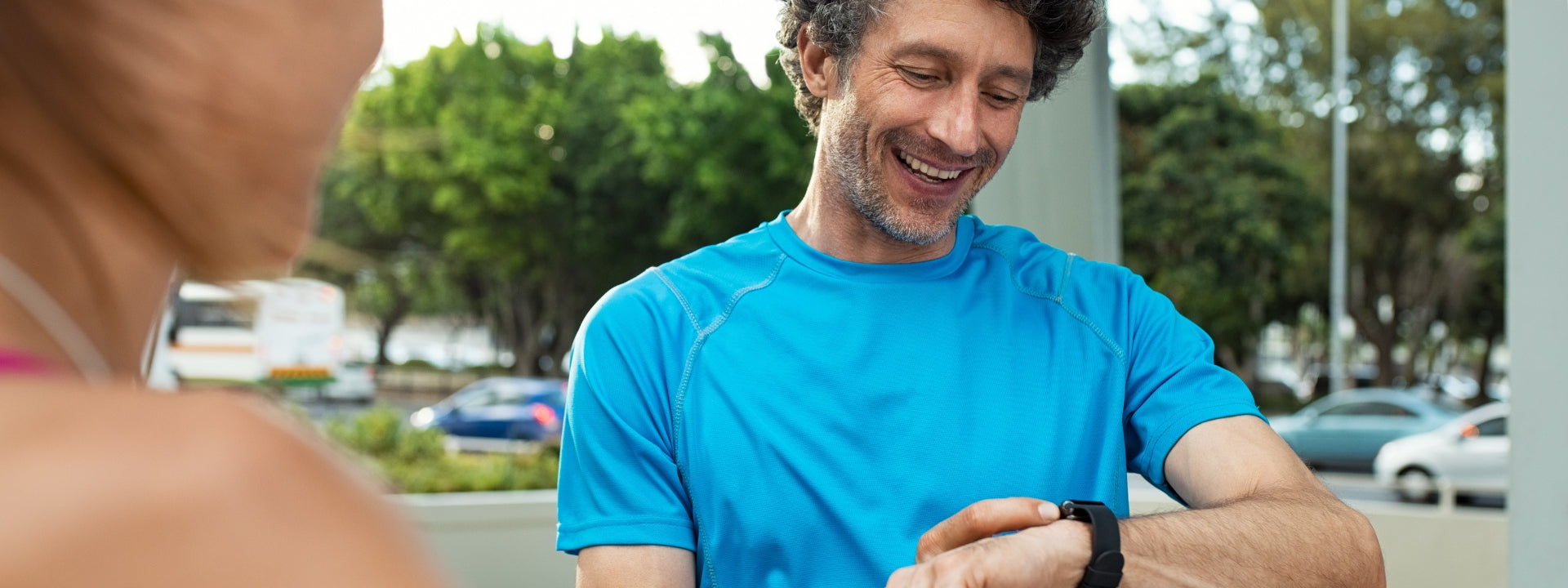 Active man, a runner, in a blue t-shirt checks his heart monitoring watch