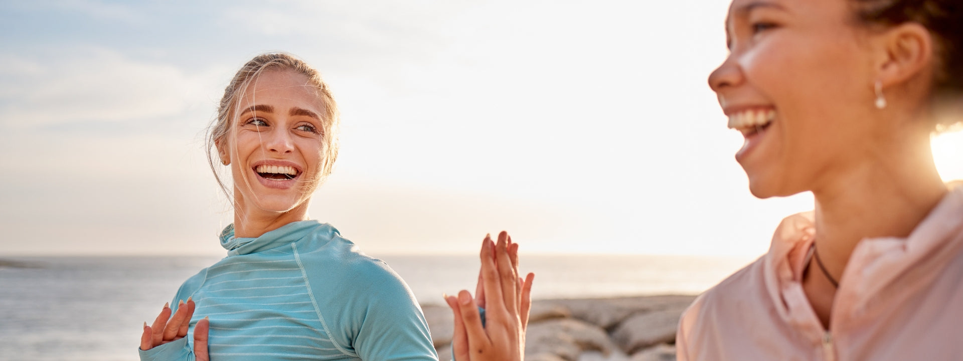 Two women do yoga on the beach