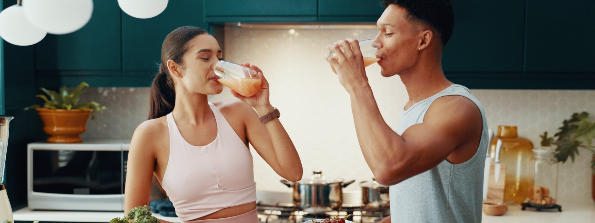 Athletic couple in the kitchen drinking smoothies