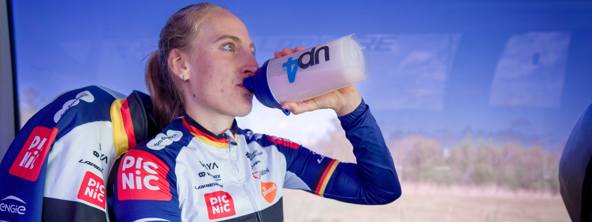 Female cyclist drinks a protein shake with Up4 on the bottle